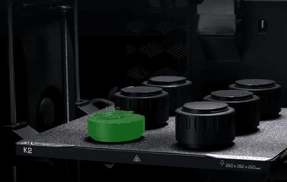 3D-printer rohelise mudeliga printimisplatvormil mustade nuppude kõrval