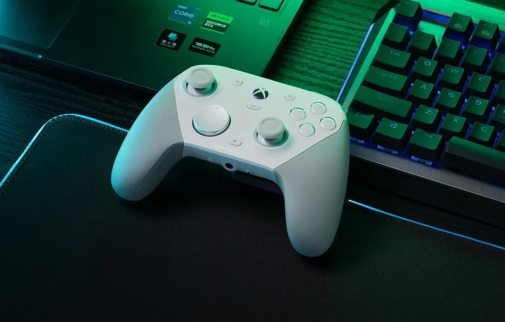 Valge GameSiri kontroller matil sülearvuti ja klaviatuuri kõrval.