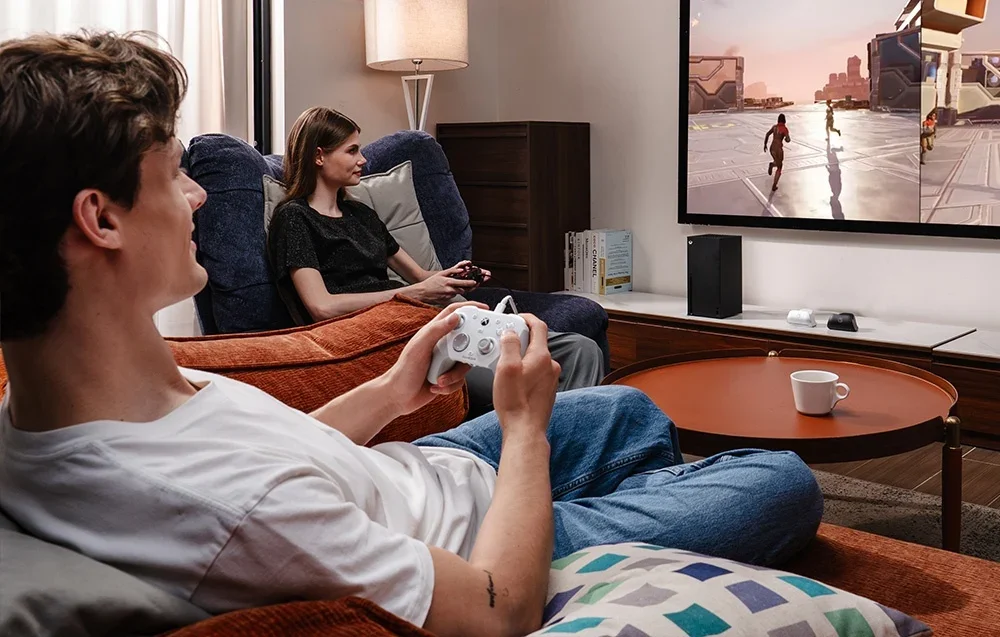Kaks inimest mängivad teleris GameSiri kontrolleritega, üks valge ja teine must.